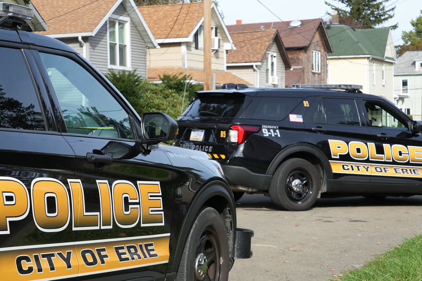 Erie police officers behind tape outside a Perry Street house